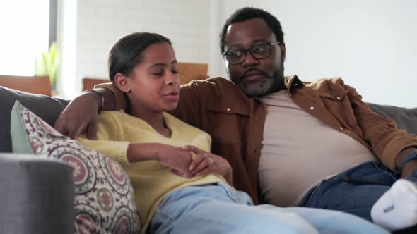 Happy father and daughter talking on the sofa