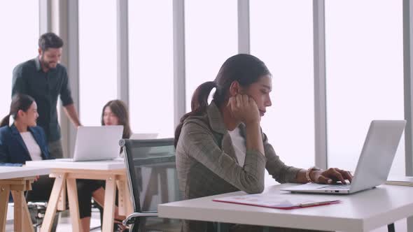 A young company employee is feeling tired while sitting at work for a long time.