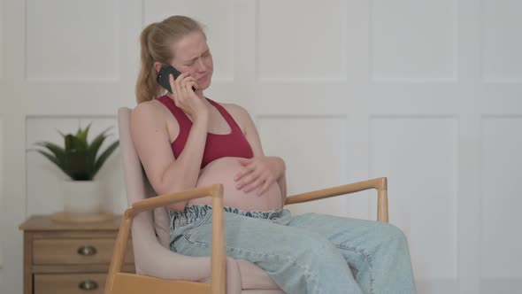Angry Pregnant Woman Talking on Phone at Home