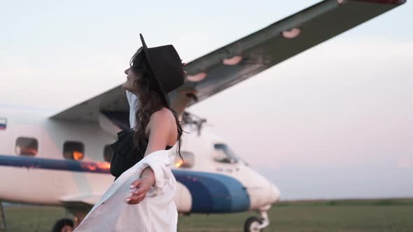 Portrait of a Beautiful Smiling Woman in a Hat at the Airport on the Background of the Plane