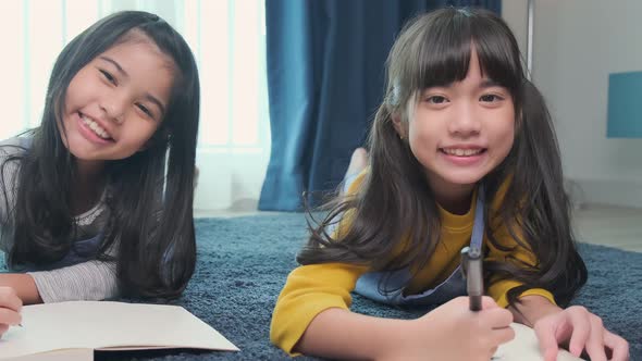 young asian daughter sibling child happiness lay down study online e-learning on floor