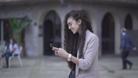 Cheerful Moroccan Girl Is Smiling While Texting On Her Smartphone Outdoor