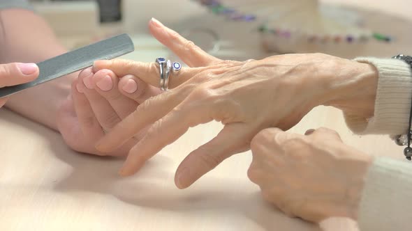 Beautician Filing Nails To Elderly Client.