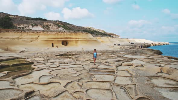 Young woman walking on salt pans in Malta