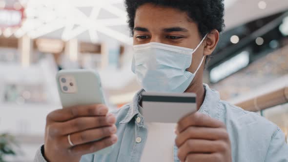 African American Man Client Customer in Medical Mask Entering Banking Credit Card Data in Phone