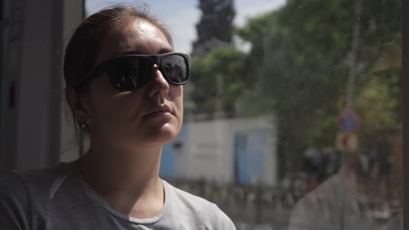 Tourist Sits at Window and Travels By Tram to City Center