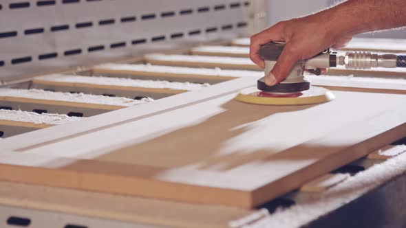 Slow motion of a worker polishing a cabinet door in a furniture factory