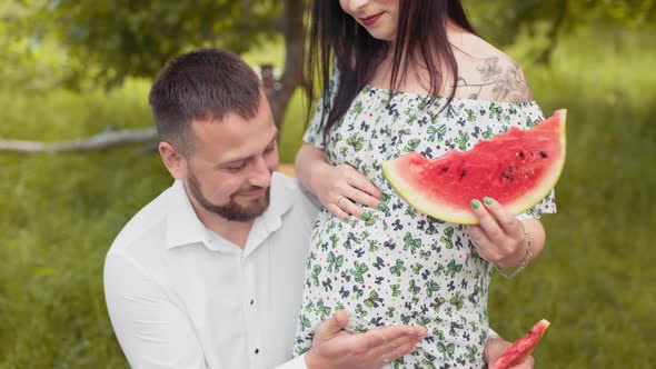 Handsome Man Kissing Pregnant Belly of His Charming Wife on Fresh Air