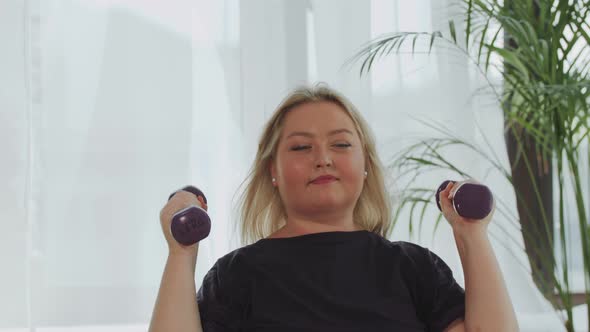 Blonde Smiling Overweight Woman Doing Fitness Exercises for Her Hands Using Dumbbells