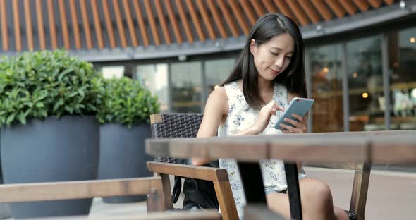 Woman using mobile phone and sitting at outdoor coffee shop