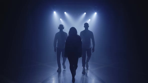 Backlit Silhouettes of Singer Vocalist Girl Saxophonist Sax Dj Man with Headphones Walking Forward