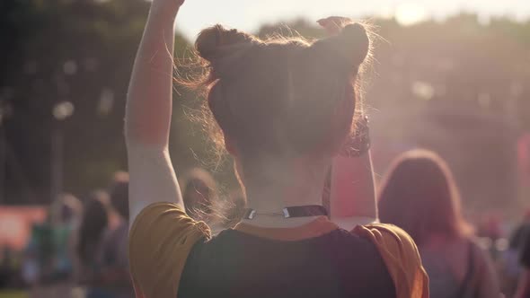 Rear view of woman dancing among bright sunbeams