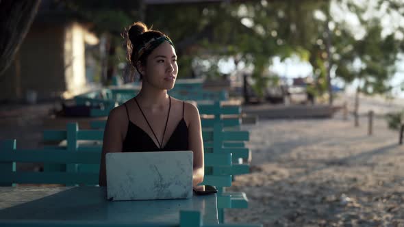 freelancer girl thinking about her next social media post on laptop at beach, Bali