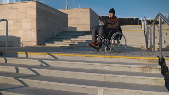 Man with Paralysis of Bottom Body Part is Sitting in Wheelchair in City Messaging By Smartphone