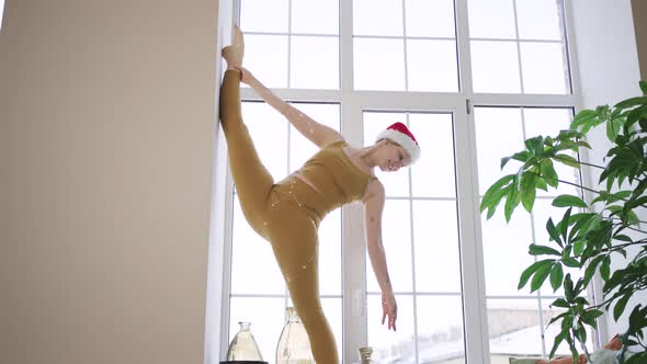 Woman Wrapped with Garland Does Vertical Split on Windowsill