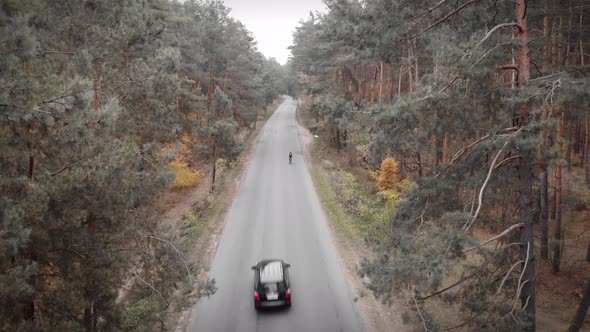 Cyclist riding bicycle on car road in autumn forest. Triathlete on road bike preparing for triathlon