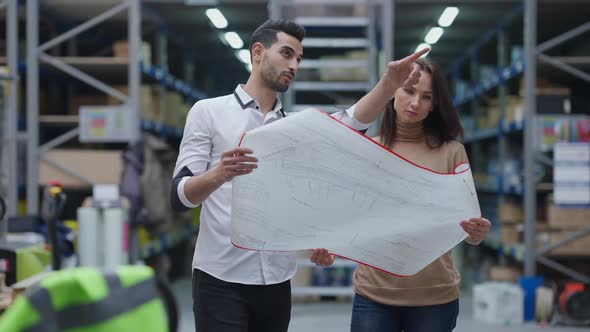 Concentrated Handsome Middle Eastern Man and Beautiful Caucasian Woman Analyzing Blueprint Standing