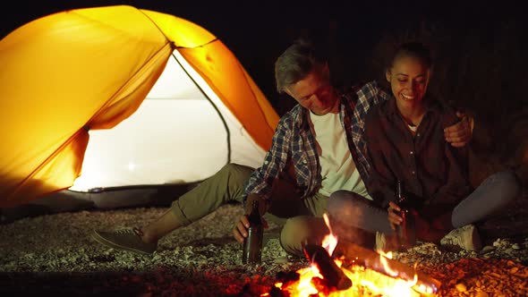 Lovely Couple Ambracing Next to Fire in Camping at Night