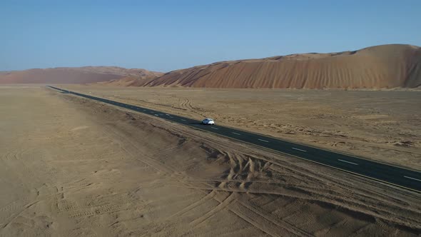 Aerial view of white car in clean road in the desert, Abu Dhabi, UAE.