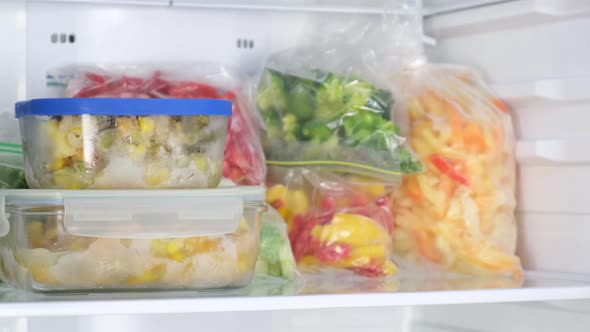 Female Hands Lay Out glass containers in the fridge.