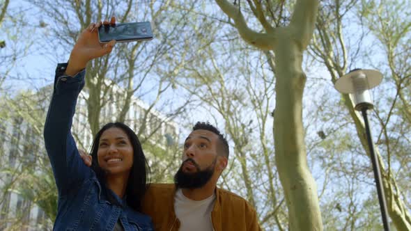 Low angle view of young mixed-race couple clicking selfie with mobile phone in the city 4k