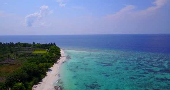 Wide birds eye travel shot of a summer white paradise sand beach and blue sea background in 4K