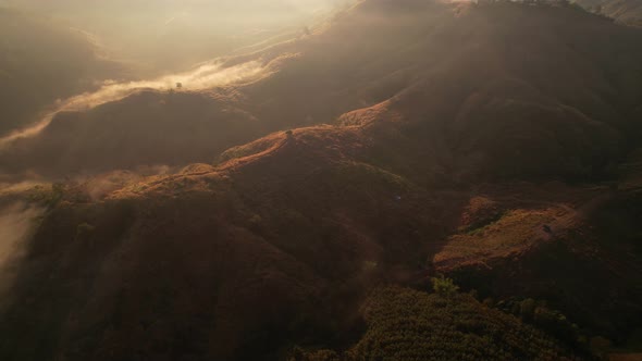 Aerial view of sunrise with fog above mountains. Golden hour and amazing sun rays. Nan, Thailand