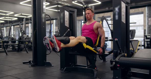 A Young Man Trains His Legs In A Leg Trainer. Pumps The Quadriceps