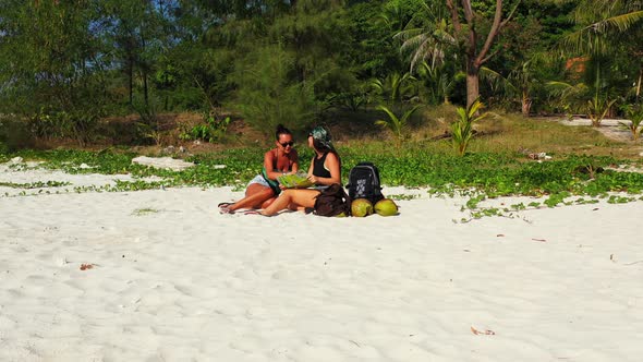 Modern smiling girls relaxing spending quality time at the beach on clean white sand and blue backgr