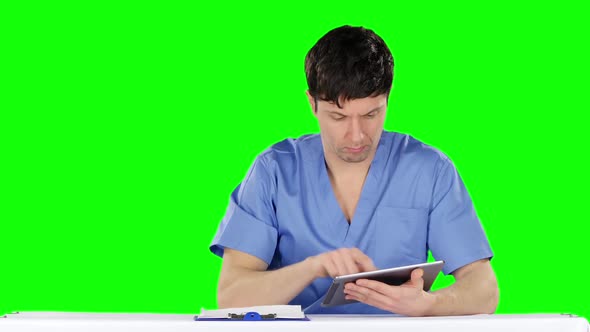 Young Doctor Uses a Tablet and Shows Thumb Down. Green Screen