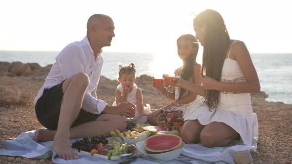 Portrait of Satisfied Caucasian Father and Daughters Posing in Sunbeam Outdoors on Picnic on Sea