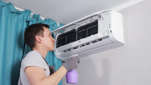 Focused Young Handyman Cleans Dust with Orange Cloth