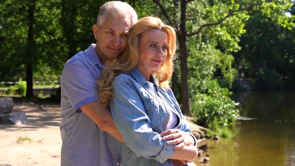Mature Couple Hugging By the Lake on a Sunny Day