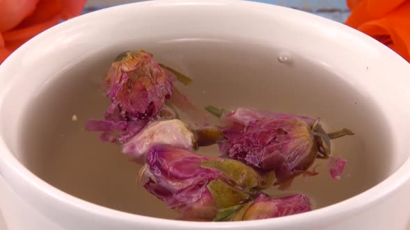 White cap of  tea with fragrant dried rose buds, fresh rose flowers