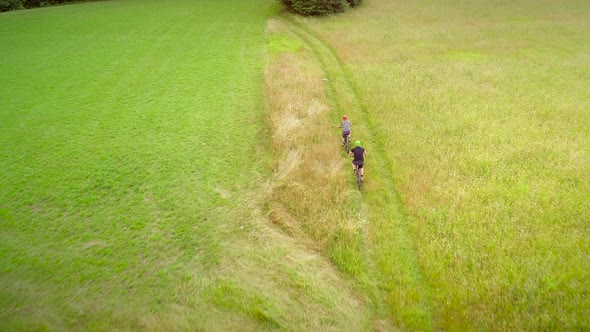 Aerial view of man and woman cycling in the forest on dirt road at Slovenia.