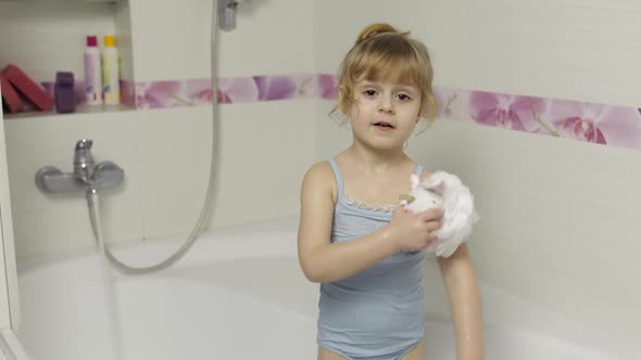 Cute Blonde Girl Takes a Bath in Swimwear. Little Child, 4 Years Old. Hygiene