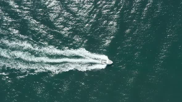top down follow drone shot of small speed boat in a blue sea alt