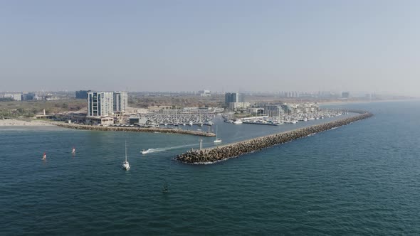 Several ships and kite surfers sail across the clear Mediterranean as they leave the marina of Herze