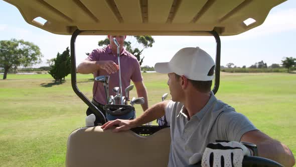 Caucasian male golfers into a golf buggy