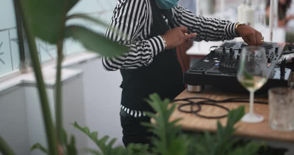 Black dj playing music at cocktail bar outdoor while wearing face safety mask