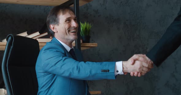 Two Mature Caucasian Businessman Handshaking at Office Meeting