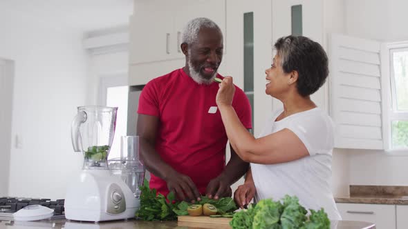 Senior african american man and woman preparing fruit and vegetable health drinks at home