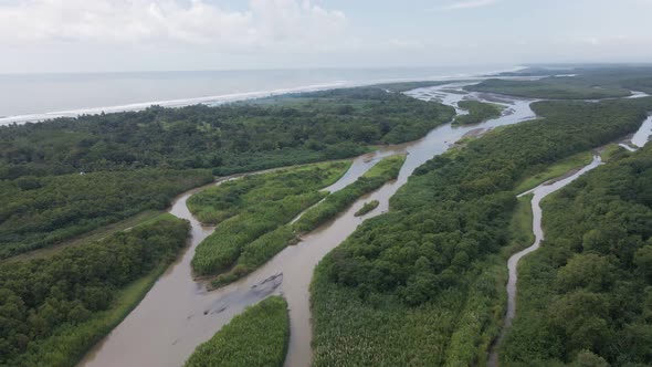 The brown rio cotos emptying into the pacific ocean on Costa Rica's tropical west coast. Aerial wide