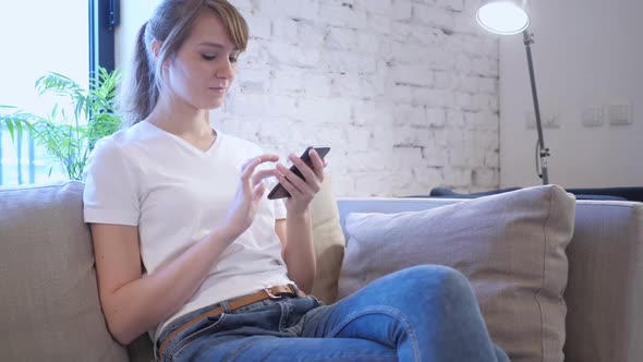 Woman Browsing Internet on Smartphone Sitting on Couch