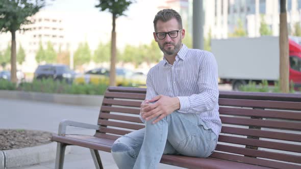 Young Adult Man Having Knee Pain While Sitting on Bench Outdoor