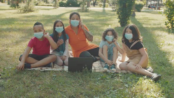 School Kids and Teacher Putting Off Medical Protective Masks Outdoors