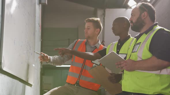 Two Caucasian and an African American male factory worker at a factory in discussion