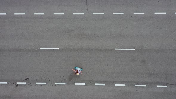 Aerial view of young woman skatboarding on empty road