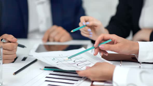 Closeup Brainstorming of Business People Hand Holding Pencil Pointing on Paper Data Profit Graphic