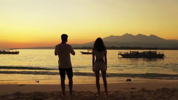 Man and woman standing together on the beach and watching the sunset and beautiful sea nature